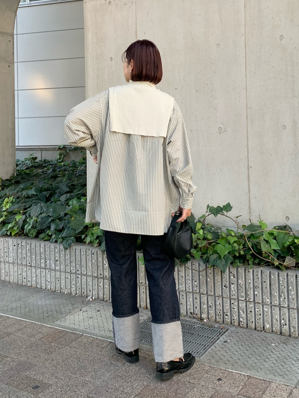 ブルー系のデニムパンツ、ブラック系のショルダーバッグ、ホワイト系のシャツ/ブラウスを着用したレディースの秋コーディネートの3枚目の写真