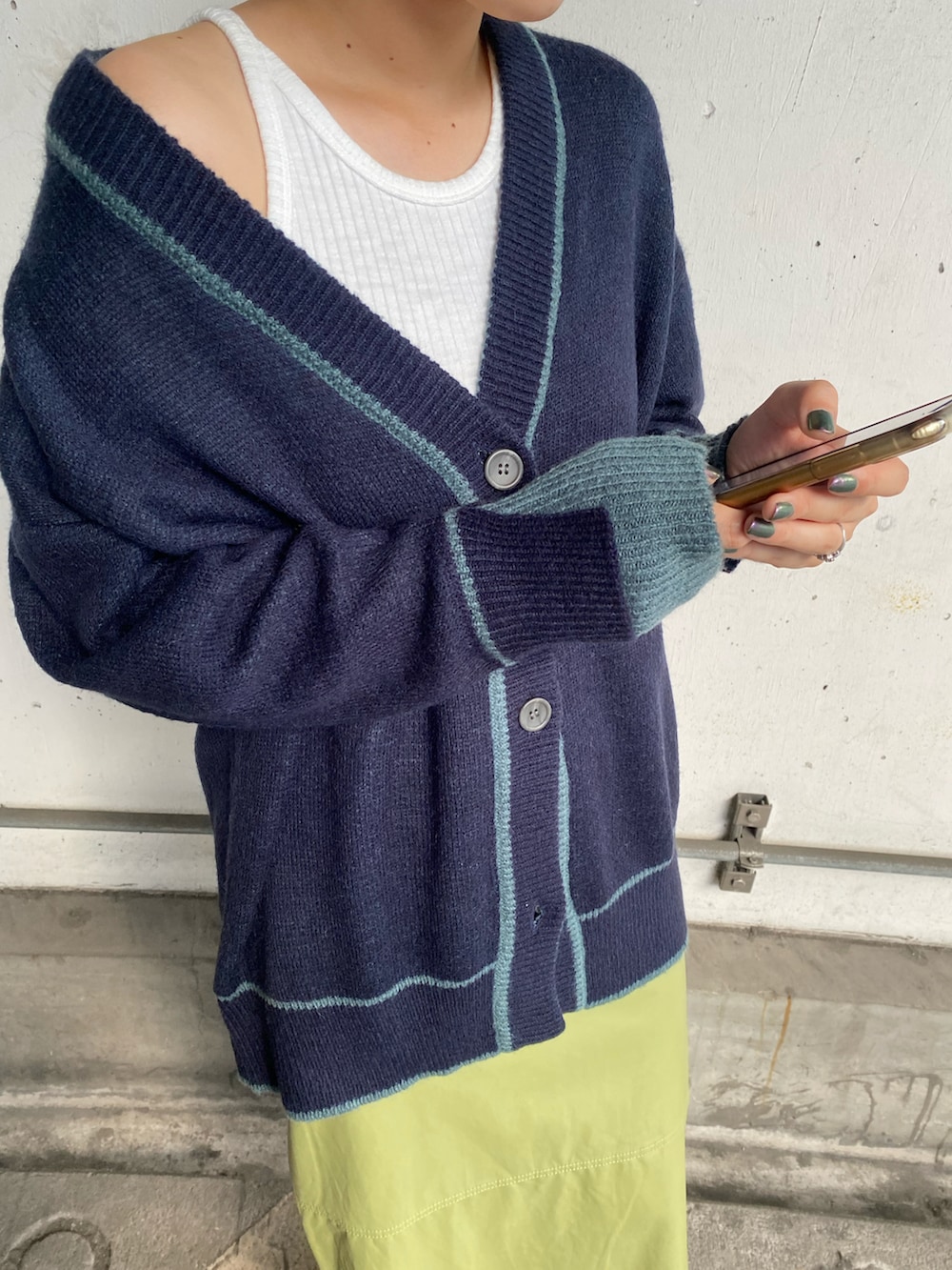 グリーン系のスカート、ブルー系のカーディガン/ボレロ、ホワイト系のタンクトップを着用したレディースの秋コーディネートの3枚目の写真