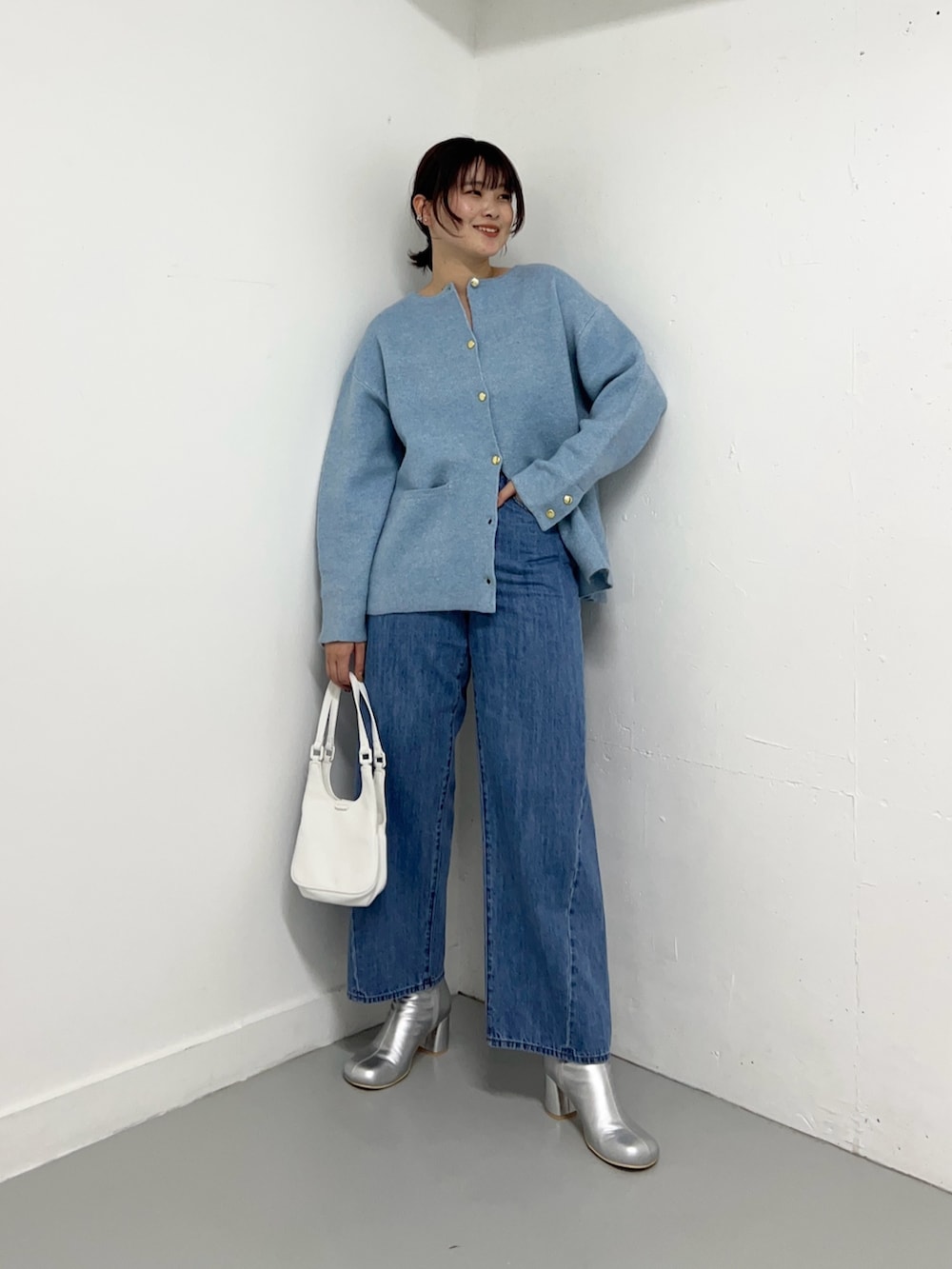 ブルー系のデニムパンツ、ブルー系のカーディガン/ボレロ、ホワイト系のハンドバッグを着用したレディースの冬コーディネートの2枚目の写真