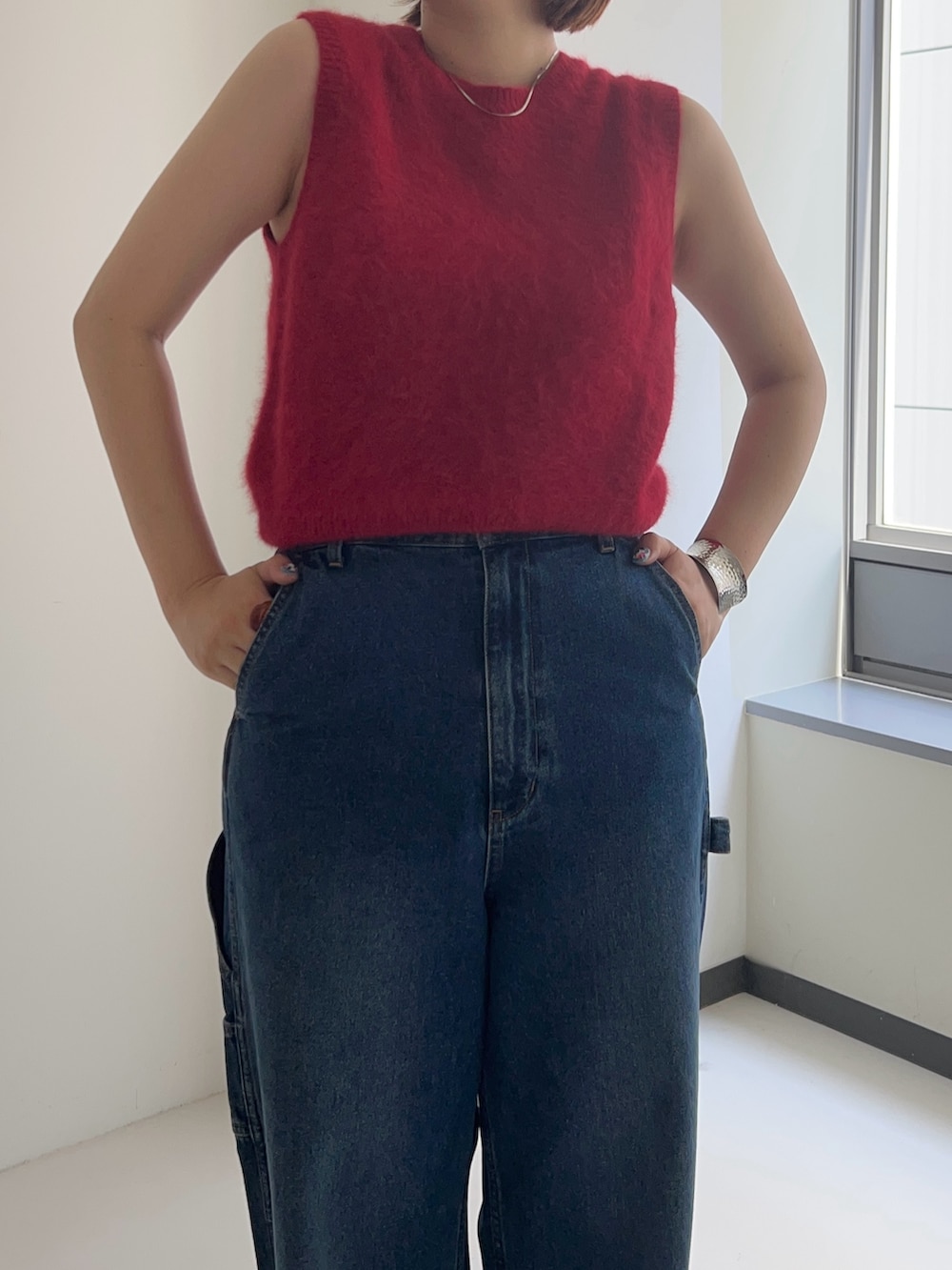 レッド系のベスト、ブルー系のデニムパンツを着用したレディースの夏コーディネートの4枚目の写真