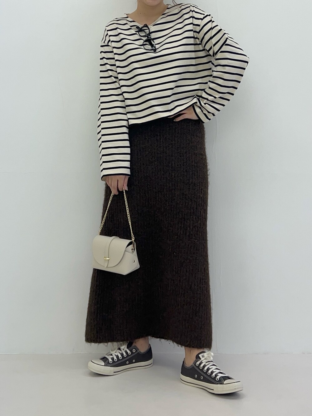 ブラウン系のスカート、ホワイト系のTシャツ/カットソー、ホワイト系のショルダーバッグを着用したレディースの冬コーディネートの3枚目の写真