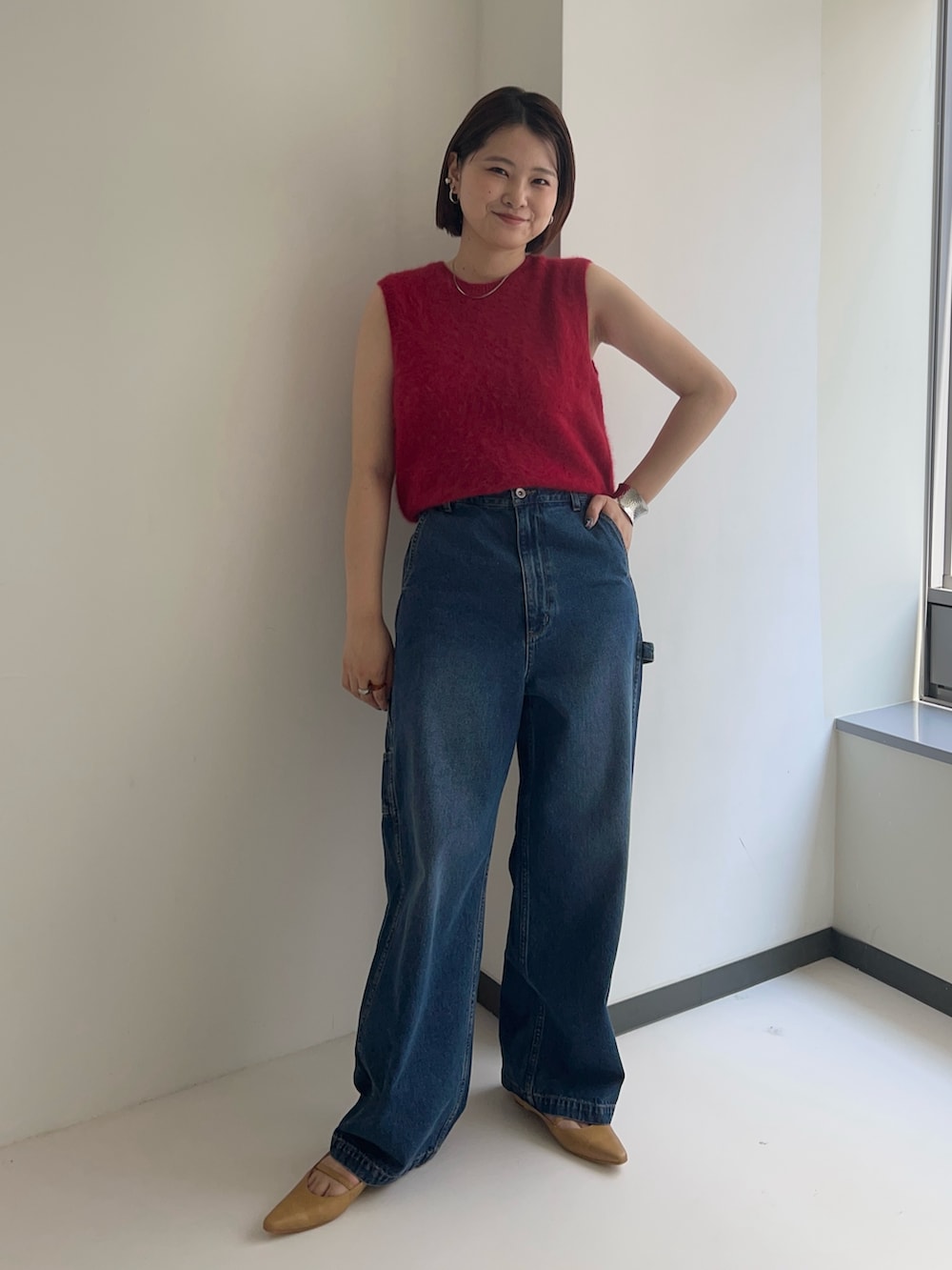 レッド系のベスト、ブルー系のデニムパンツを着用したレディースの夏コーディネートの2枚目の写真