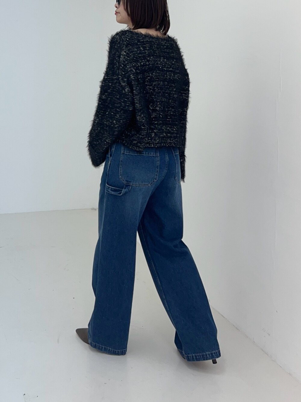 ブラック系のニット/セーター、ブルー系のデニムパンツを着用したレディースの秋コーディネートの4枚目の写真