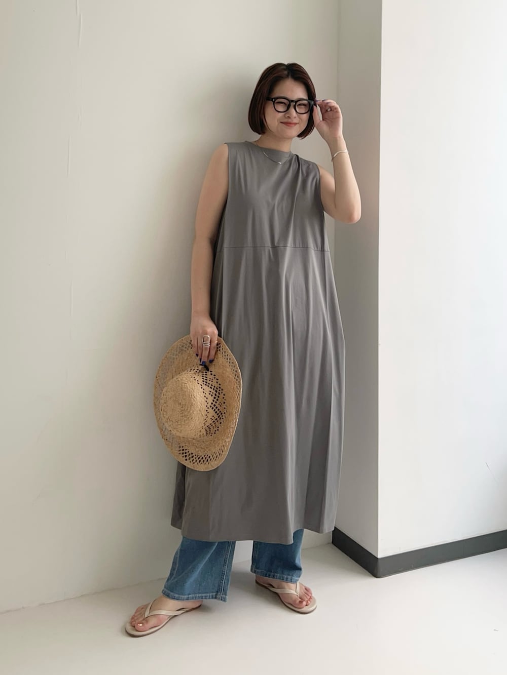 グレー系のワンピース、ブルー系のデニムパンツ、シルバー系のネックレスを着用したレディースの夏コーディネートの2枚目の写真