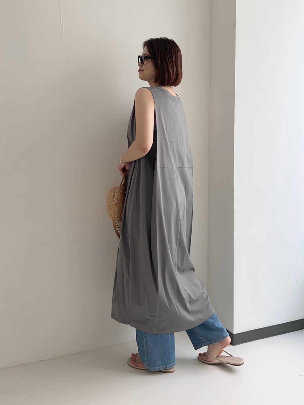 グレー系のワンピース、ブルー系のデニムパンツ、シルバー系のネックレスを着用したレディースの夏コーディネートの3枚目の写真