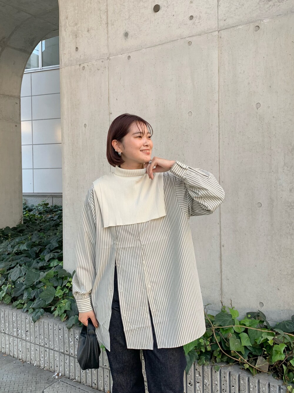 ブルー系のデニムパンツ、ブラック系のショルダーバッグ、ホワイト系のシャツ/ブラウスを着用したレディースの秋コーディネートの4枚目の写真