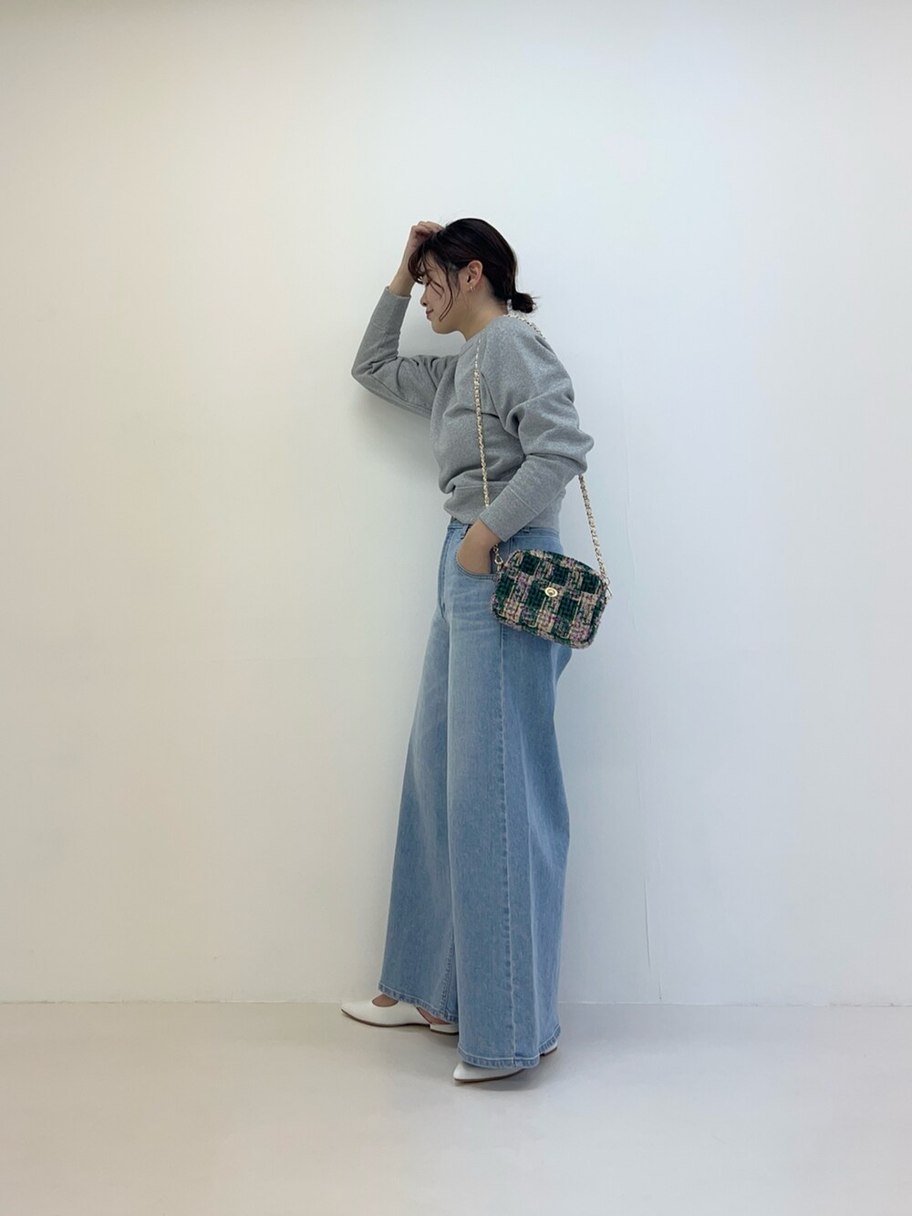 グレー系のTシャツ/カットソー、ブルー系のデニムパンツ、グリーン系のショルダーバッグを着用したレディースの冬コーディネートの3枚目の写真