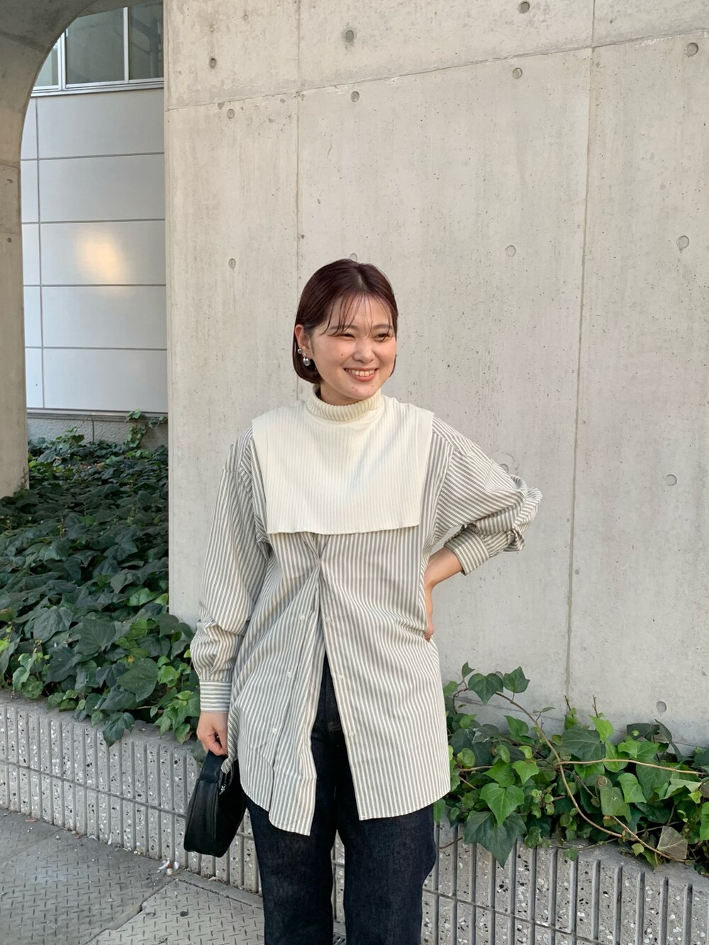 ブルー系のデニムパンツ、ブラック系のショルダーバッグ、ホワイト系のシャツ/ブラウスを着用したレディースの秋コーディネートの5枚目の写真