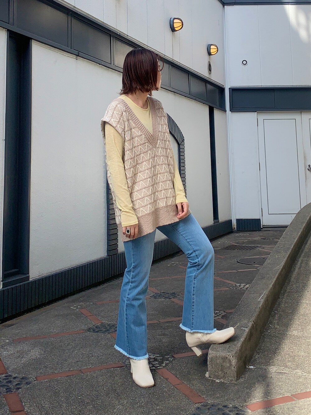 ブルー系のデニムパンツ、ベージュ系のベスト、イエロー系のTシャツ/カットソーを着用したレディースの春コーディネートの2枚目の写真