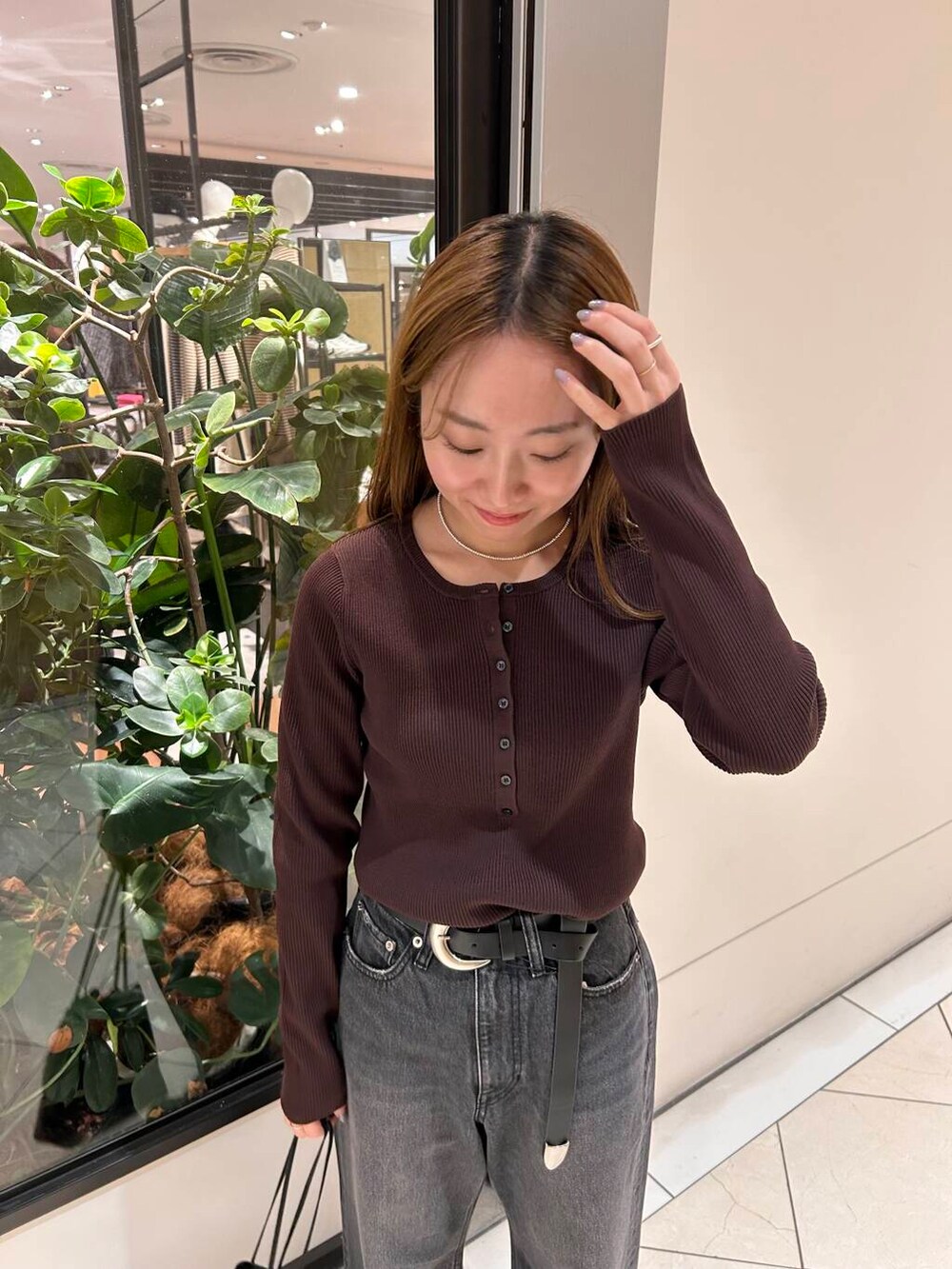 ブラック系のショルダーバッグ、ブラック系のデニムパンツ、ブラウン系のニット/セーターを着用したレディースの秋コーディネートの3枚目の写真