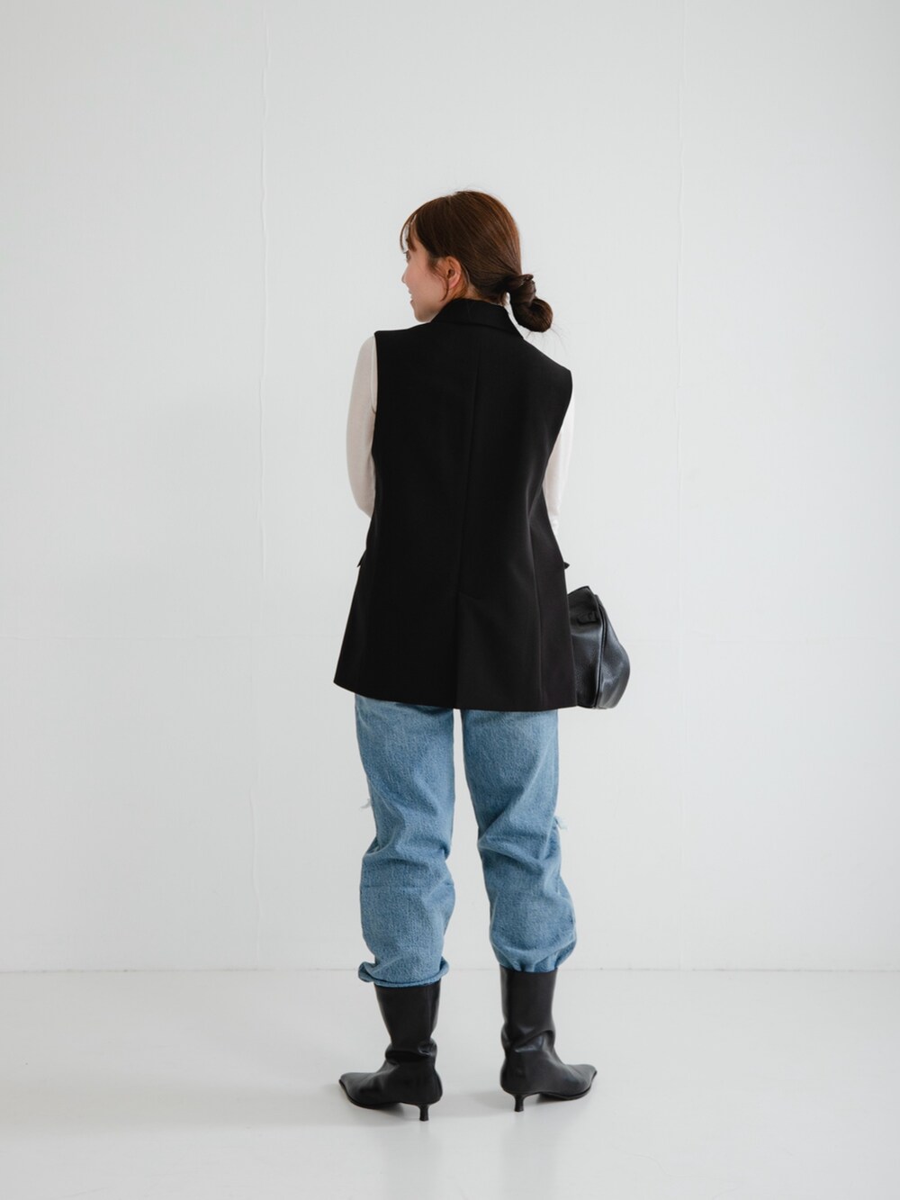 ブラック系のブーツ、ブルー系のデニムパンツ、ブラック系のその他アウターを着用したレディースの冬コーディネートの2枚目の写真
