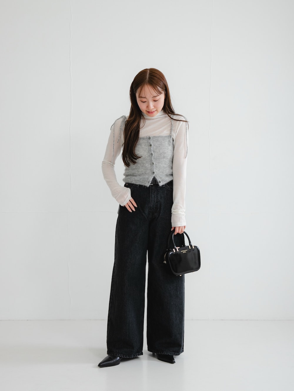 ブラック系のデニムパンツ、ブラック系のブーツ、ブラック系のショルダーバッグを着用したレディースの冬コーディネートの2枚目の写真