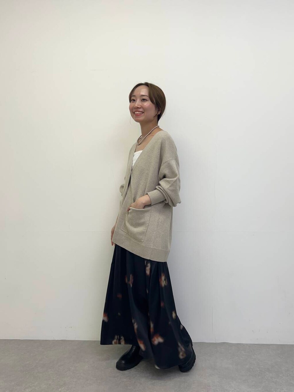 ホワイト系のキャミソール、ベージュ系のカーディガン/ボレロ、ブラック系のブーツを着用したレディースの秋コーディネートの2枚目の写真