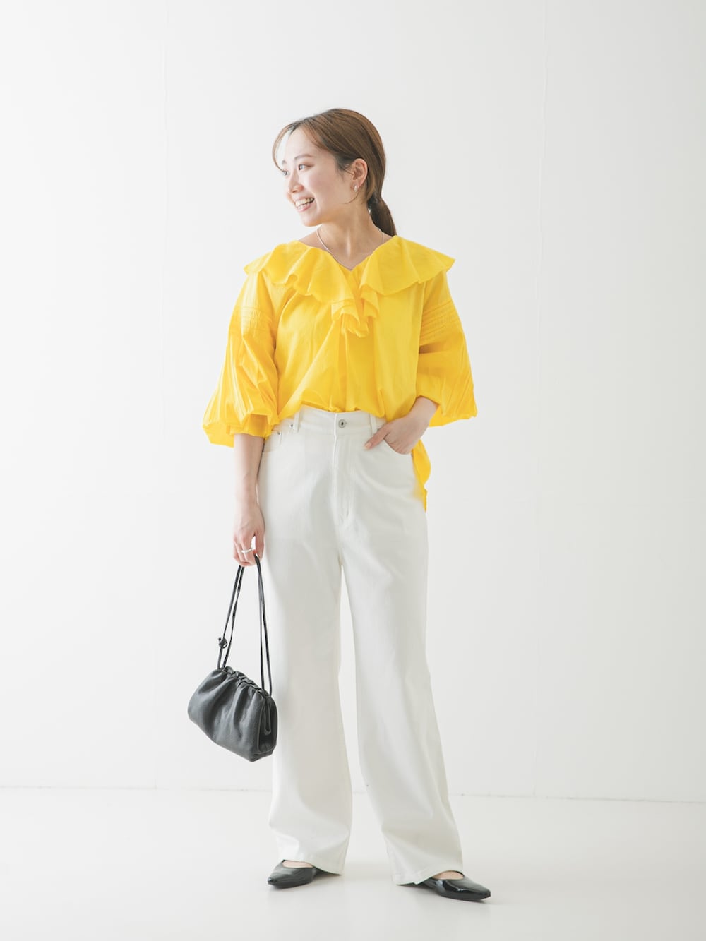 ブラック系のパンプス、ブラック系のショルダーバッグ、ホワイト系のデニムパンツを着用したレディースの春コーディネートの2枚目の写真