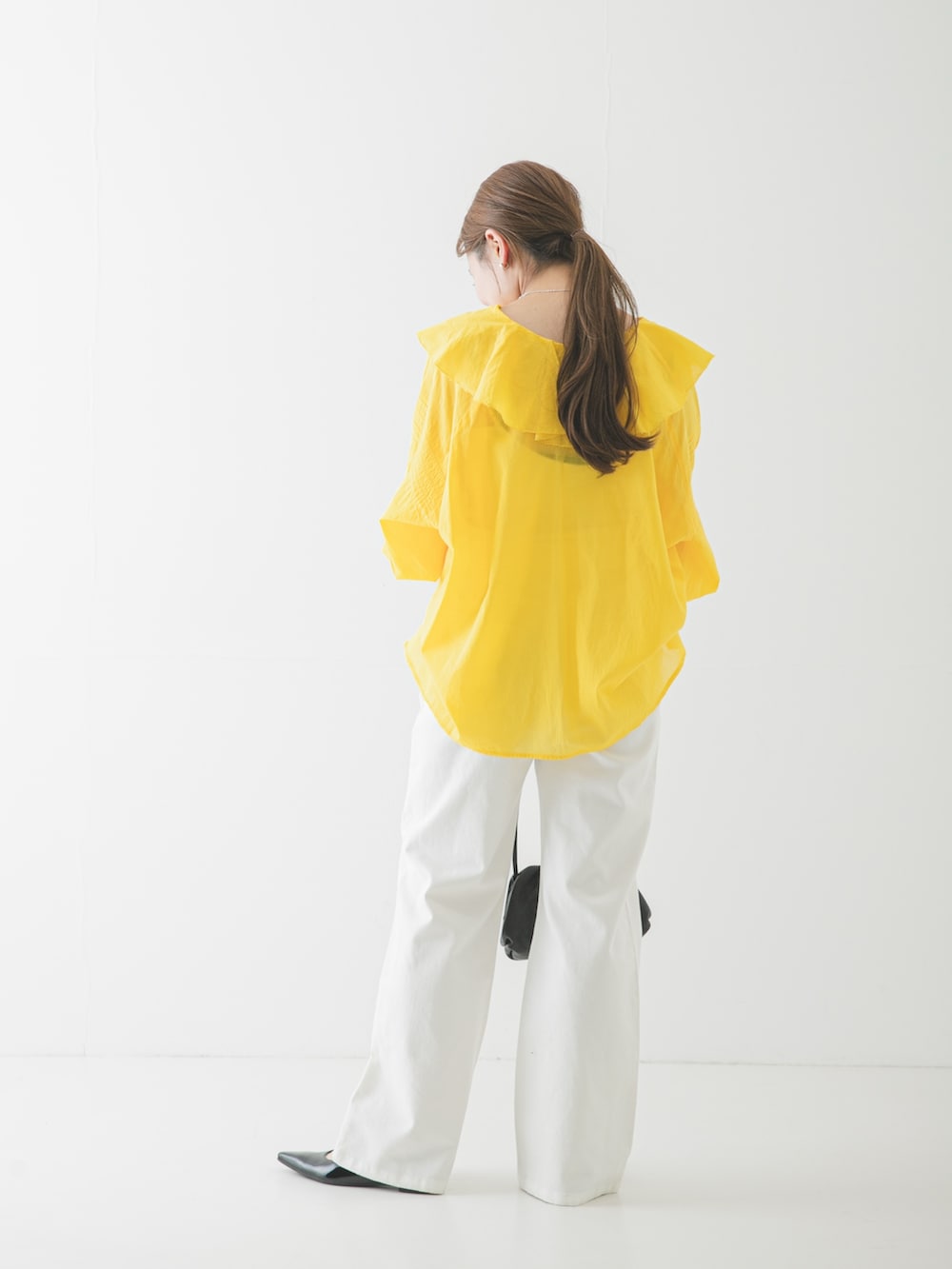 ブラック系のパンプス、ブラック系のショルダーバッグ、ホワイト系のデニムパンツを着用したレディースの春コーディネートの3枚目の写真