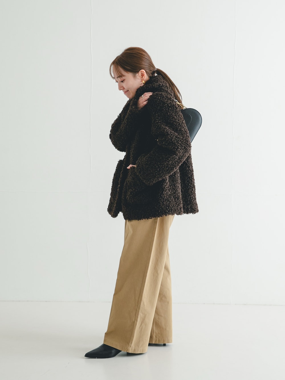 ブラック系のブーツ、ブラウン系のその他アウター、ブラック系のニット/セーターを着用したレディースの冬コーディネートの3枚目の写真