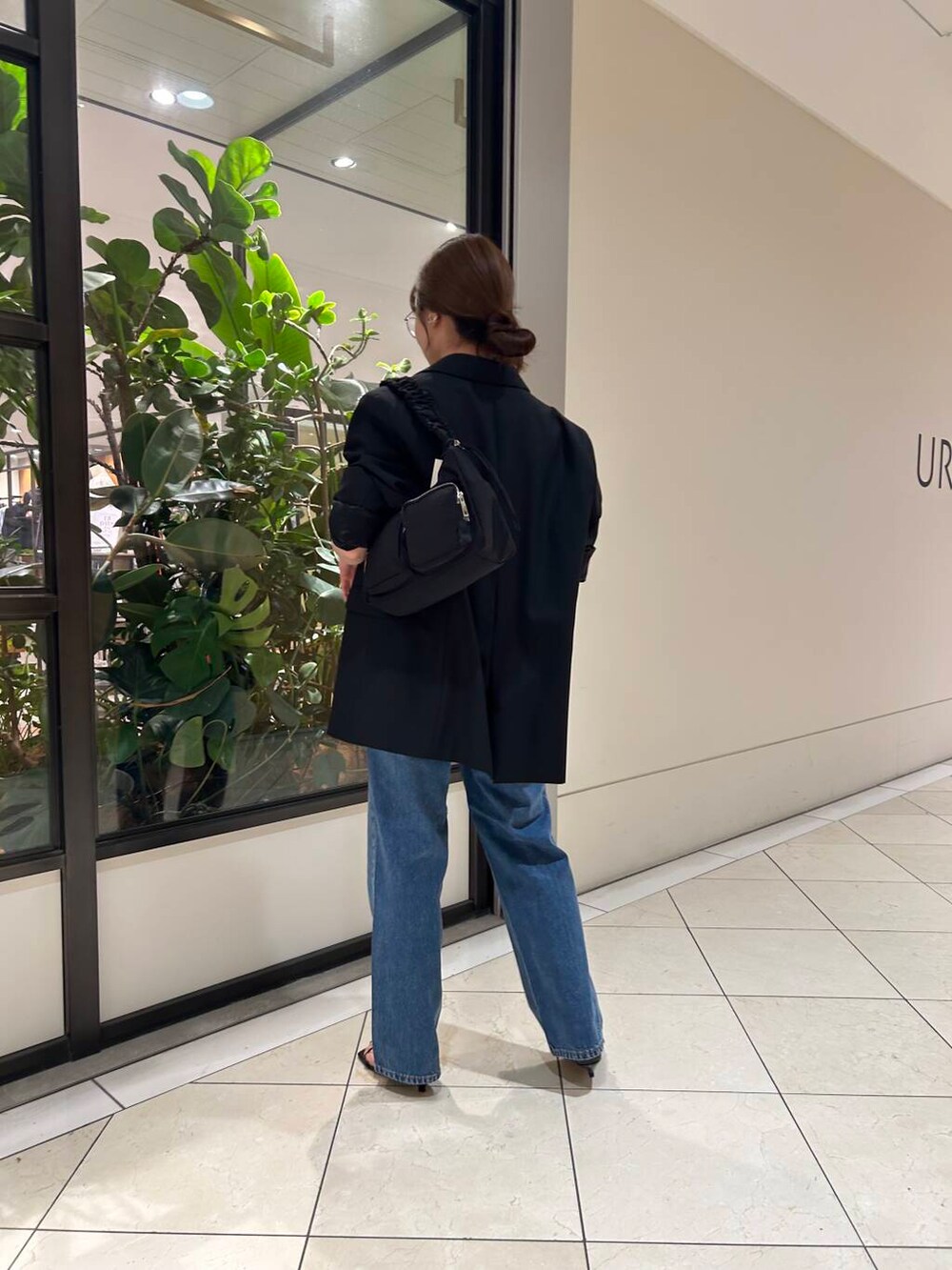 ブラック系のサンダル、ブラック系のショルダーバッグ、ブルー系のデニムパンツを着用したレディースの秋コーディネートの2枚目の写真