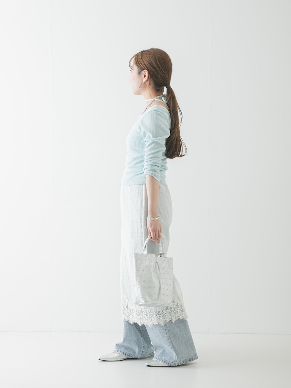 シルバー系のパンプス、ブルー系のデニムパンツ、ホワイト系のスカートを着用したレディースの春コーディネートの2枚目の写真