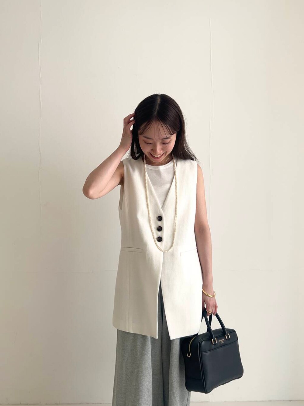 ホワイト系のベスト、ブラック系のバレエシューズ、グレー系のその他パンツを着用したレディースの夏コーディネートの3枚目の写真