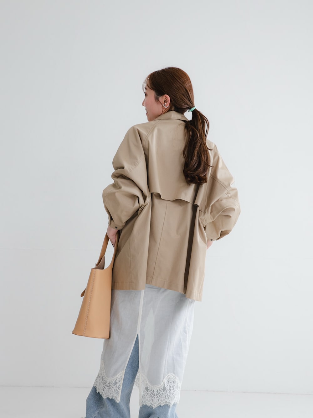 ブルー系のデニムパンツ、ホワイト系のスニーカー、ホワイト系のスカートを着用したレディースの冬コーディネートの3枚目の写真