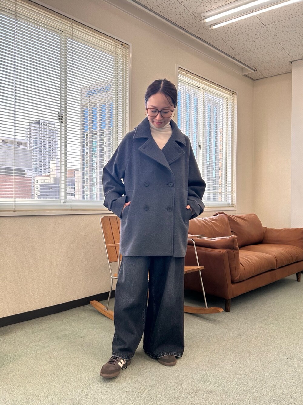 グレー系のピーコート、ブラック系のデニムパンツを着用したレディースの秋コーディネートの2枚目の写真