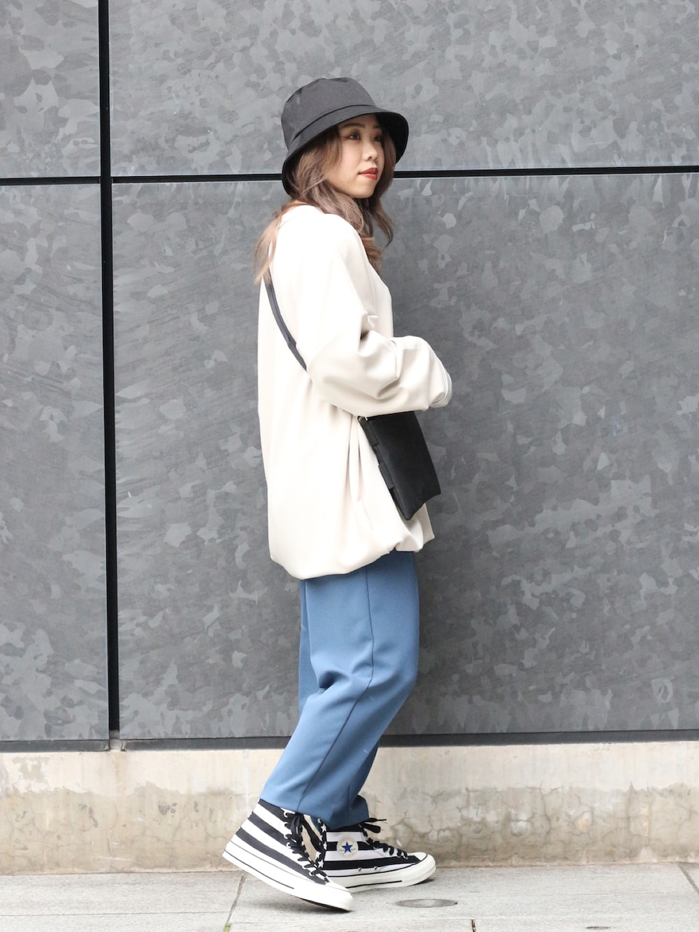 ホワイト系のトップス、ブラック系のボディバッグ/ウエストポーチ、ブルー系のスラックスを着用したレディースの冬コーディネートの2枚目の写真