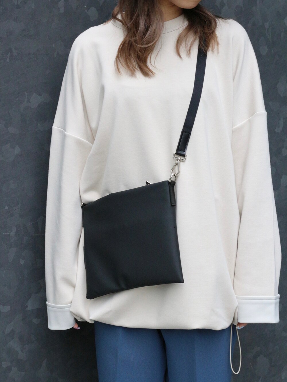 ホワイト系のトップス、ブラック系のボディバッグ/ウエストポーチ、ブルー系のスラックスを着用したレディースの冬コーディネートの3枚目の写真