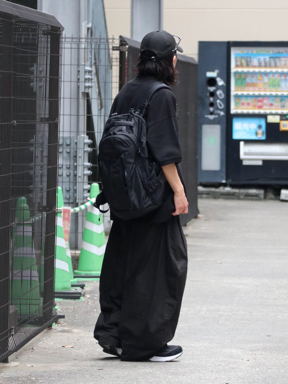 ブラック系のポロシャツ、ブラック系のチノパンツ、ブラック系のスニーカーを着用したメンズの春コーディネートの3枚目の写真
