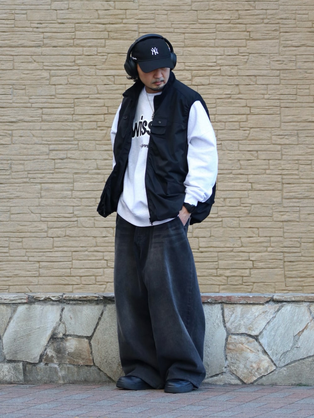 グレー系のスウェット、ブラック系のベストを着用したメンズの春コーディネートの2枚目の写真