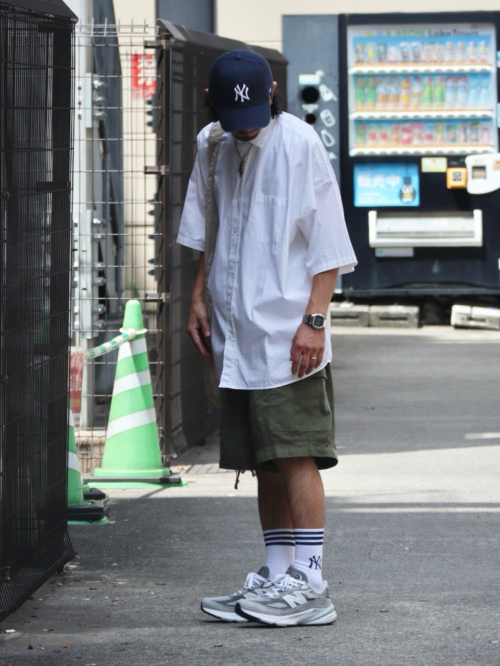 グリーン系のカーゴパンツ、グレー系のスニーカー、ブルー系のキャップを着用したメンズの夏コーディネートの2枚目の写真