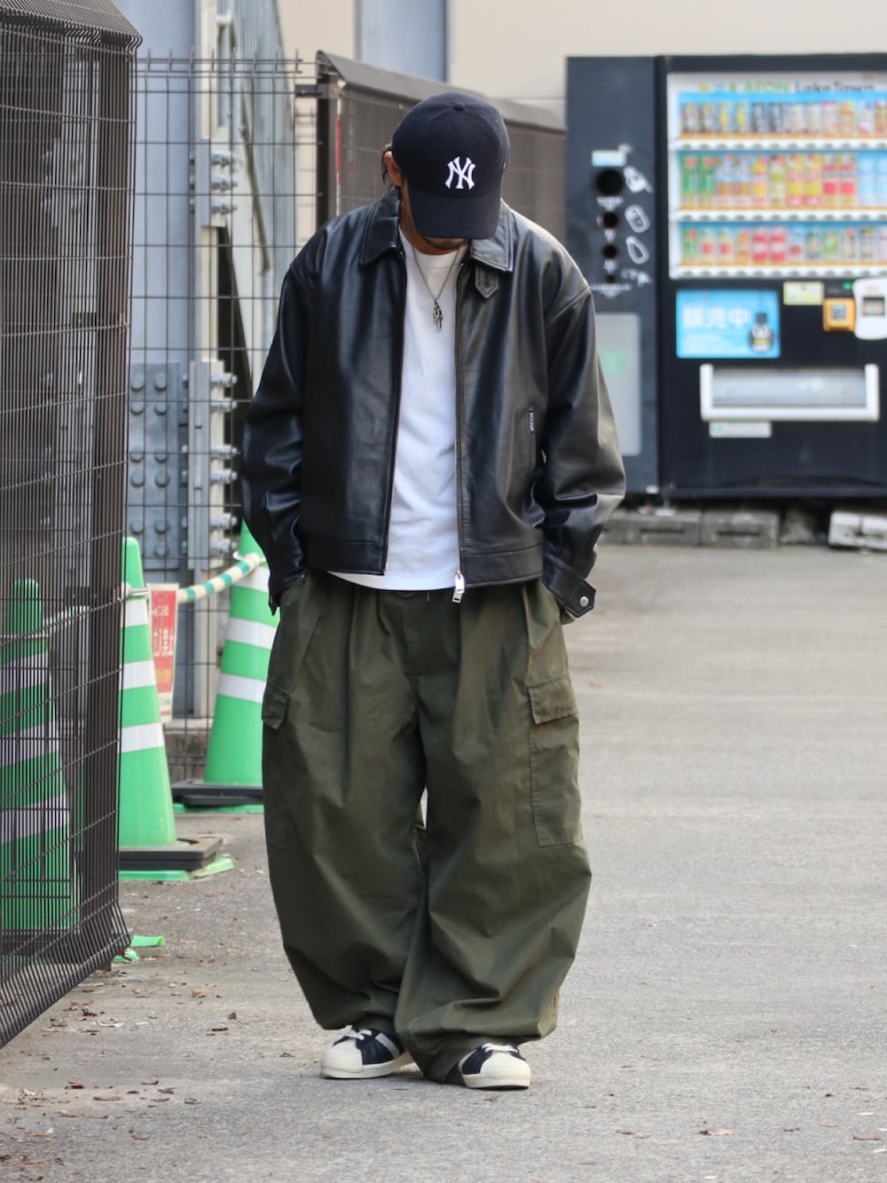 ブラック系のライダースジャケット、グリーン系のその他パンツ、シルバー系のピアス（片耳用）を着用したメンズの秋コーディネートの2枚目の写真