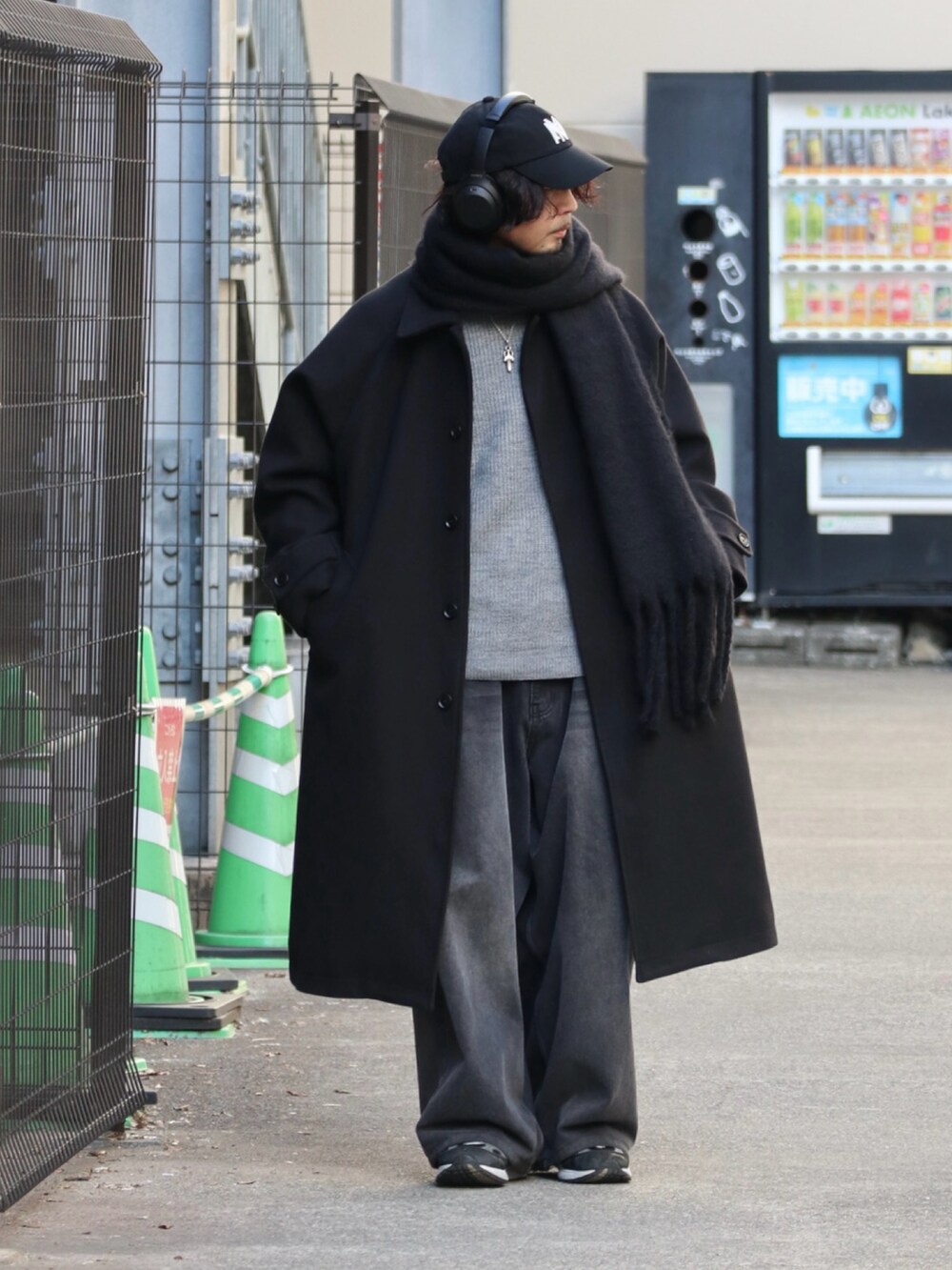 ブラック系のステンカラーコート、グレー系のニット/セーター、ブラック系のデニムパンツを着用したメンズの冬コーディネートの4枚目の写真