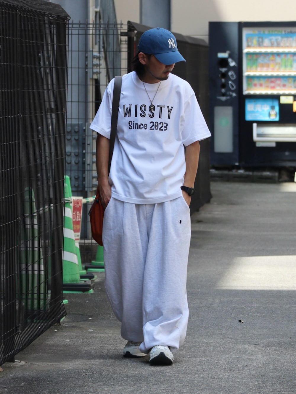 ホワイト系のTシャツ/カットソー、オレンジ系のショルダーバッグ、シルバー系のピアス（片耳用）を着用したメンズの夏コーディネートの3枚目の写真