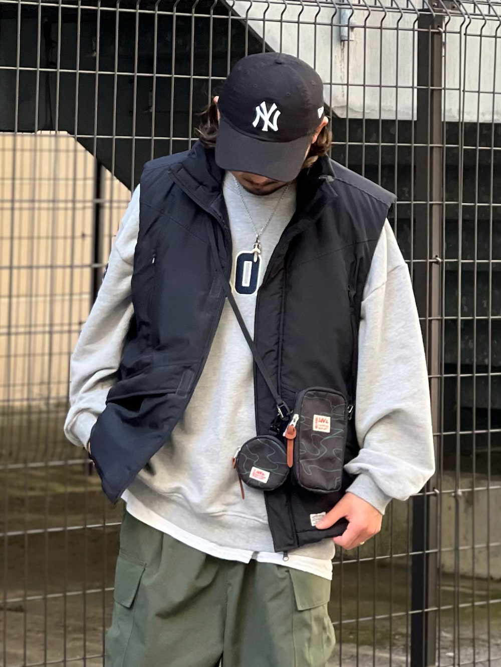 ブラック系のショルダーバッグ、グリーン系のカーゴパンツ、ブラック系のダウンベストを着用したメンズの冬コーディネートの2枚目の写真