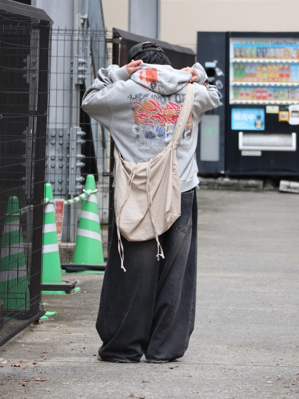 グレー系のパーカー、ブラック系のスニーカー、シルバー系のピアス（片耳用）を着用したメンズの秋コーディネートの3枚目の写真