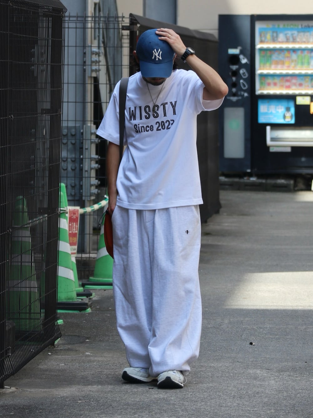 ホワイト系のTシャツ/カットソー、オレンジ系のショルダーバッグ、シルバー系のピアス（片耳用）を着用したメンズの夏コーディネートの2枚目の写真