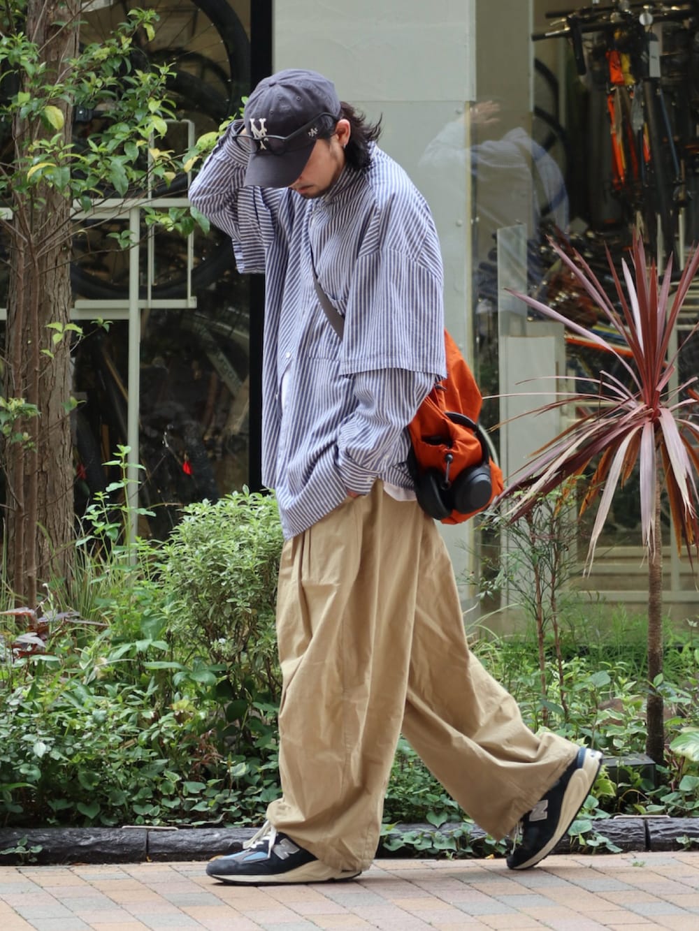 オレンジ系のショルダーバッグ、ブルー系のキャップを着用したメンズの春コーディネートの2枚目の写真