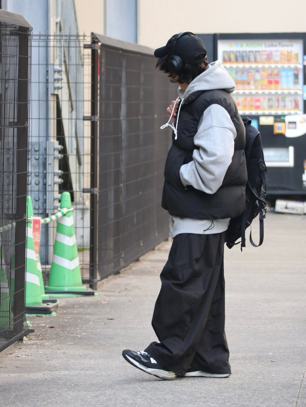 ブラック系のダウンベスト、グレー系のパーカー、ブラック系のチノパンツを着用したメンズの冬コーディネートの3枚目の写真