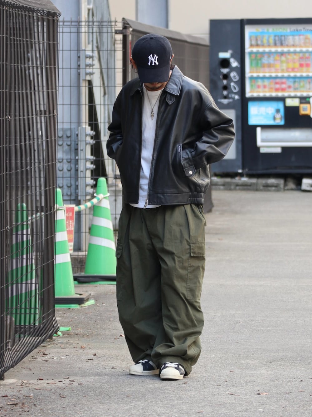 ブラック系のライダースジャケット、グリーン系のその他パンツ、シルバー系のピアス（片耳用）を着用したメンズの秋コーディネートの3枚目の写真