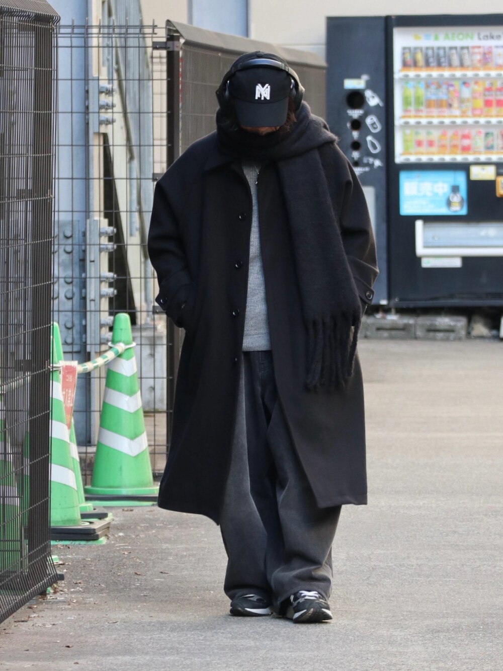 ブラック系のステンカラーコート、グレー系のニット/セーター、ブラック系のデニムパンツを着用したメンズの冬コーディネートの2枚目の写真