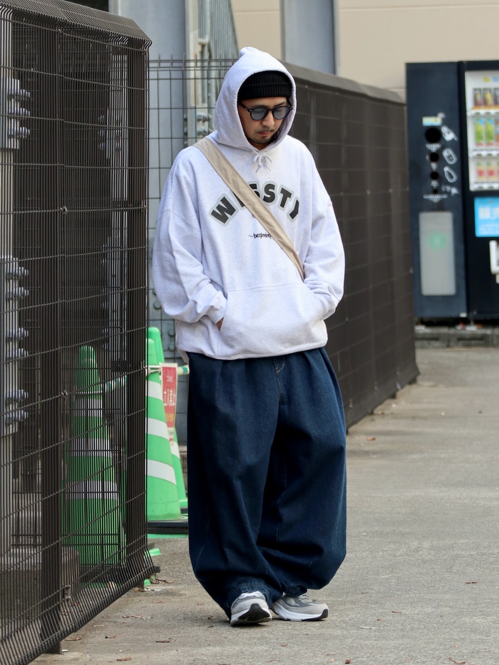 グレー系のスウェット、ブルー系のデニムパンツ、グレー系のスニーカーを着用したメンズの秋コーディネートの2枚目の写真