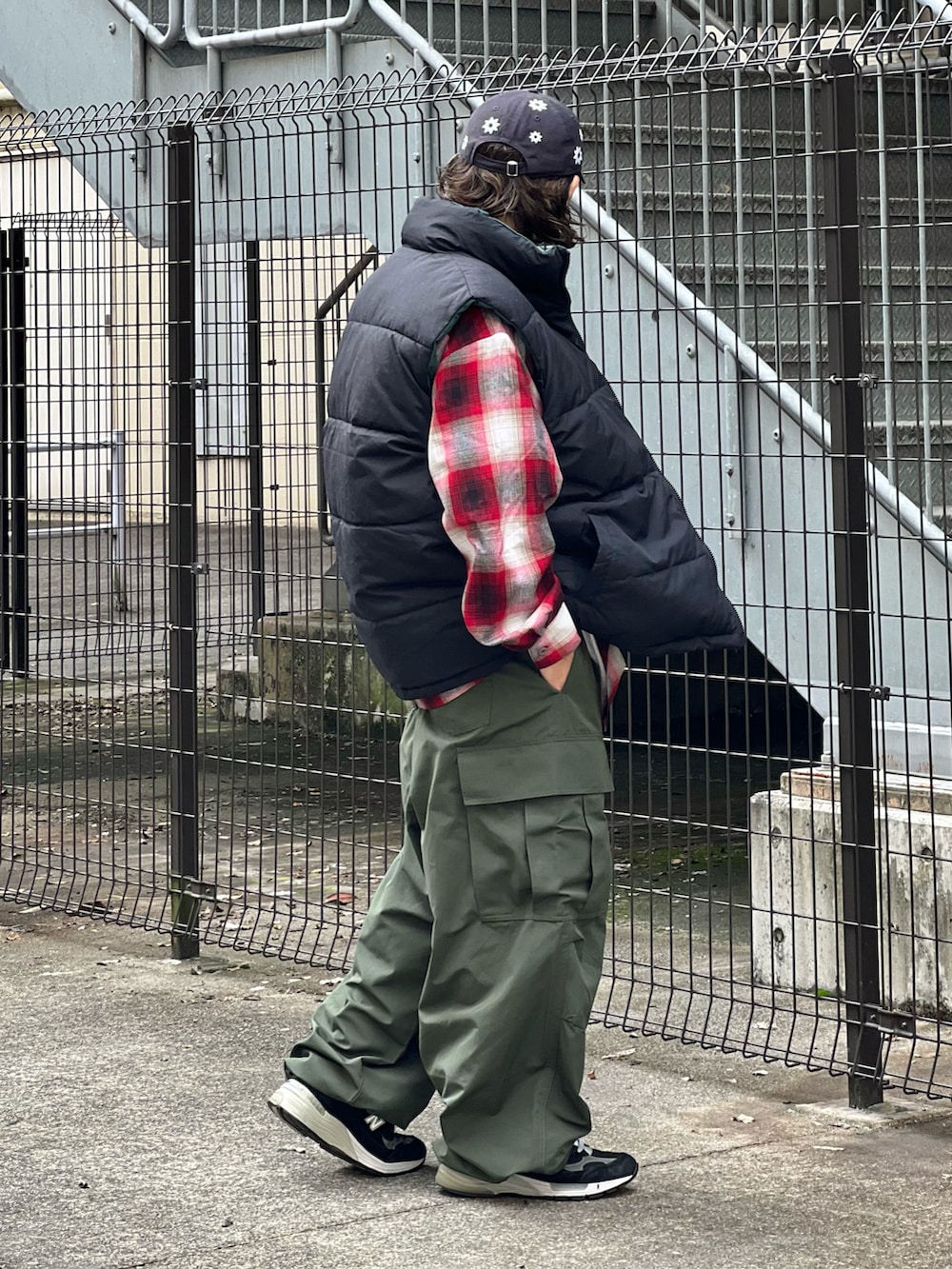 グリーン系のカーゴパンツ、レッド系のシャツ/ブラウス、ブラック系のダウンベストを着用したメンズの冬コーディネートの2枚目の写真