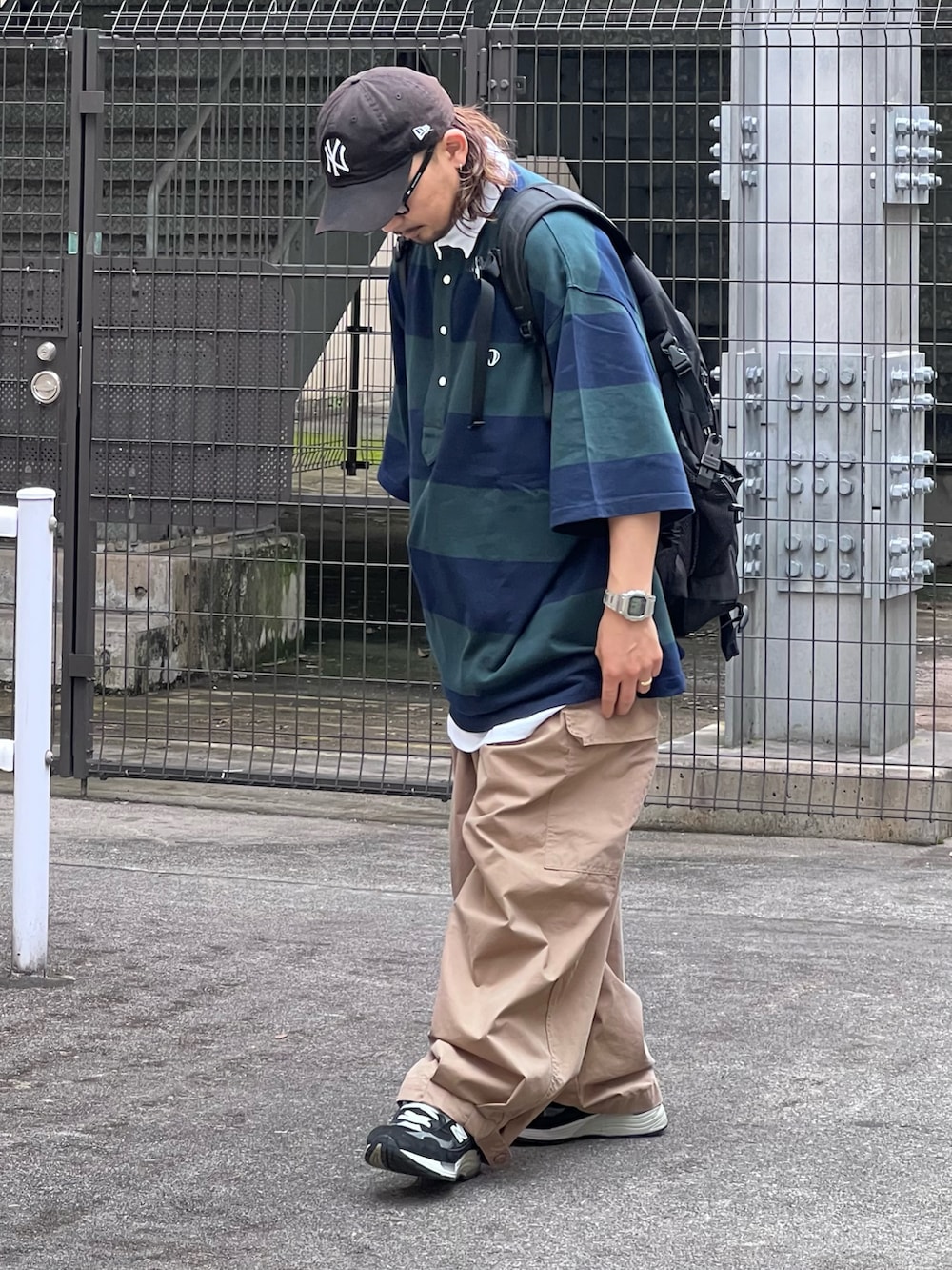 グリーン系のポロシャツ、ベージュ系のその他パンツ、ブラック系のスニーカーを着用したメンズの夏コーディネートの2枚目の写真