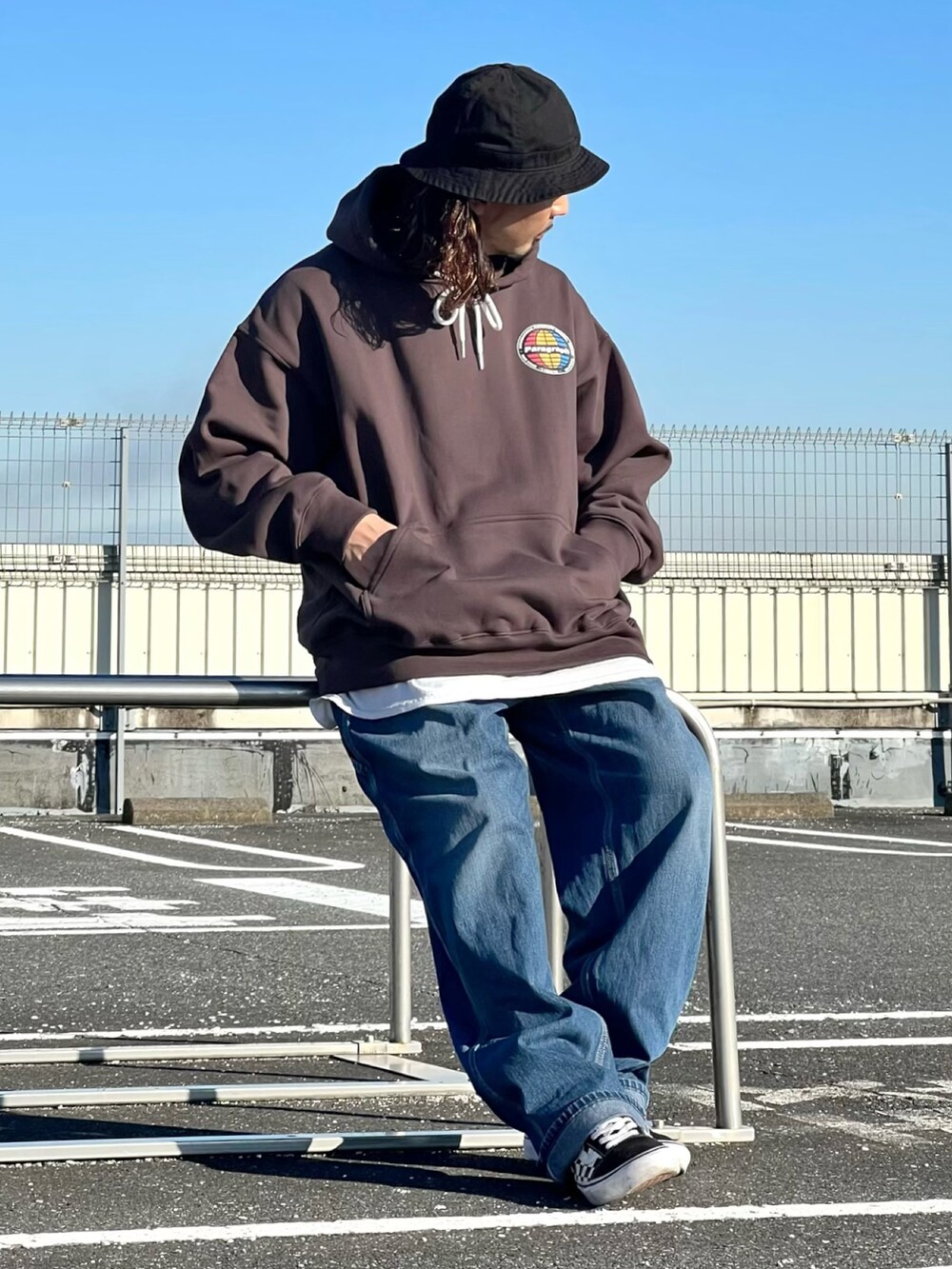 ブラウン系のパーカー、ブラック系のスニーカー、ブラック系のハットを着用したメンズの秋コーディネートの2枚目の写真