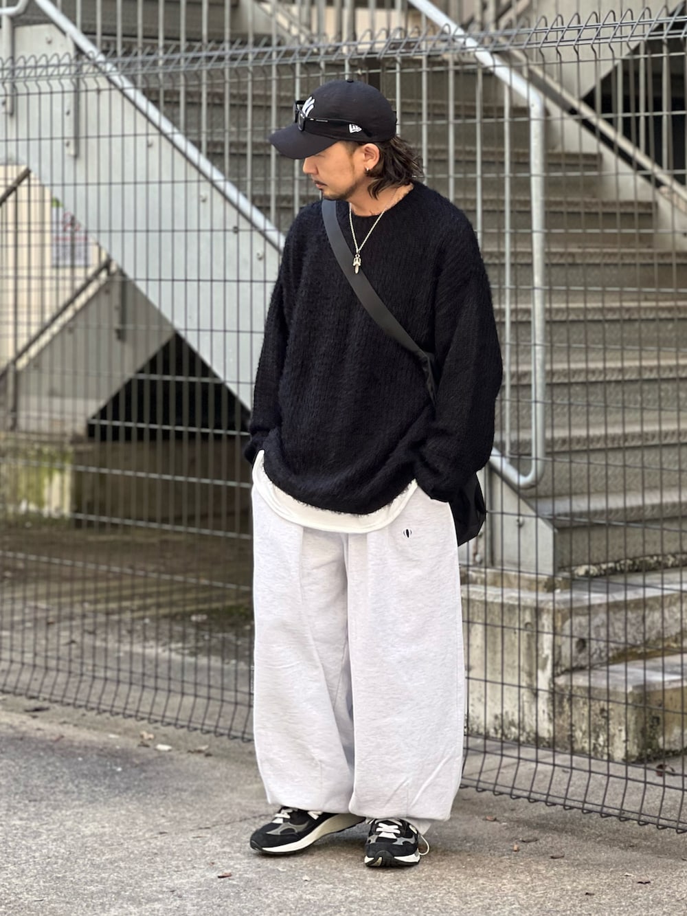 ブラック系のニット/セーター、ホワイト系のスウェットパンツ、ブラック系のスニーカーを着用したメンズの秋コーディネートの2枚目の写真