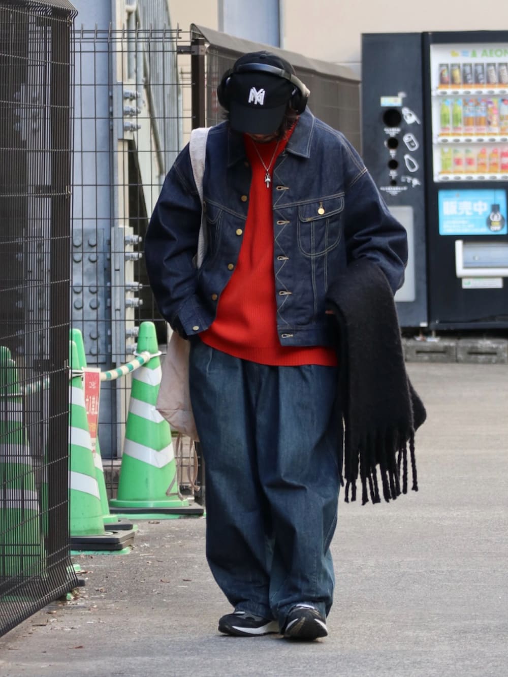 ブラック系のデニムジャケット、オレンジ系のニット/セーター、ブルー系のデニムパンツを着用したメンズの冬コーディネートの2枚目の写真