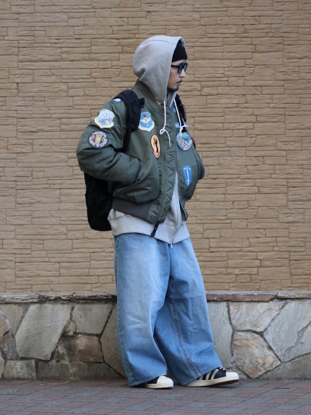 グレー系のパーカー、ブルー系のデニムパンツを着用したメンズの冬コーディネートの2枚目の写真