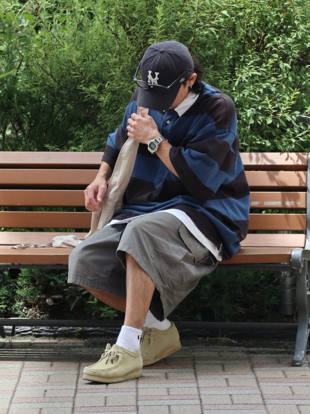 ブルー系のポロシャツ、ベージュ系のモカシン/デッキシューズ、シルバー系のピアス（片耳用）を着用したメンズの夏コーディネートの2枚目の写真