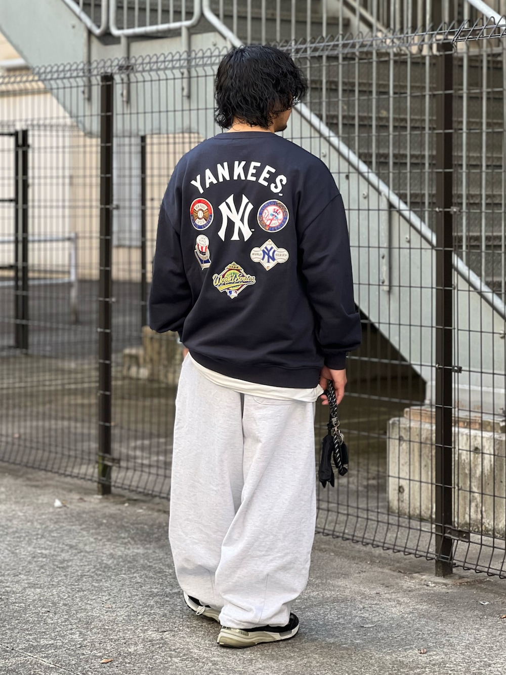 ブルー系のスウェット、ホワイト系のスウェットパンツ、ブラック系のスマホケース/カバーを着用したメンズの春コーディネートの2枚目の写真