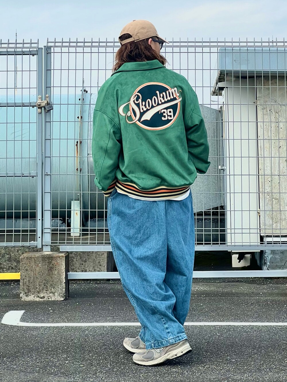 グリーン系のスタジャン、ブルー系のデニムパンツ、ベージュ系のキャップを着用したメンズの春コーディネートの3枚目の写真